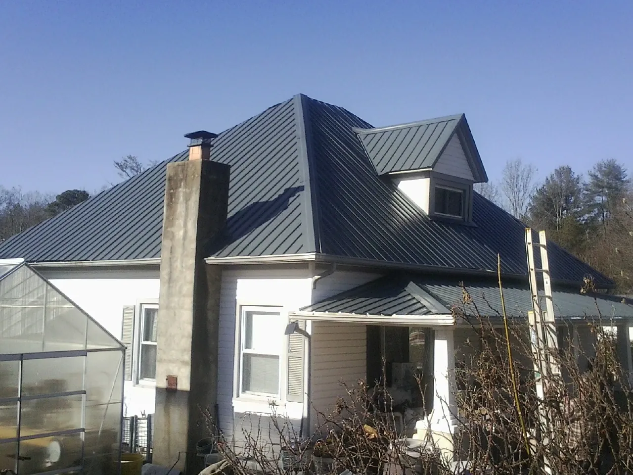 Dark blue standing seam metal roof on a white farmhouse with dormer — Slate & Tile Roof Repair by Roofing Brothers in Skokie