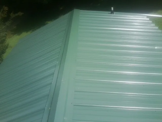 New green metal panels meeting at the ridge of a roof — Flat Roof Repair work by our crew in Skokie