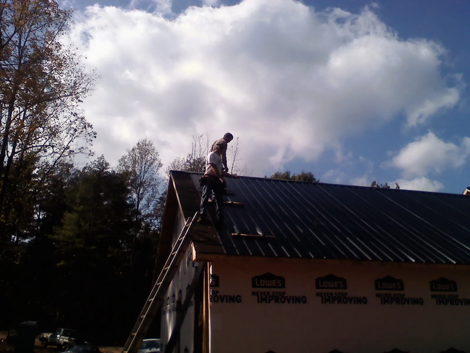 Roofer fastening dark metal panels high against a cloudy sky in Skokie
