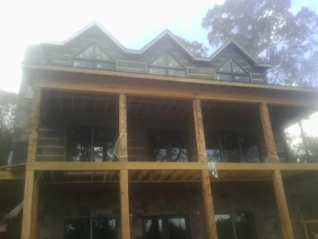 Dormers and porch framing on a large log home under construction — Roof Coating work by our crew in Skokie