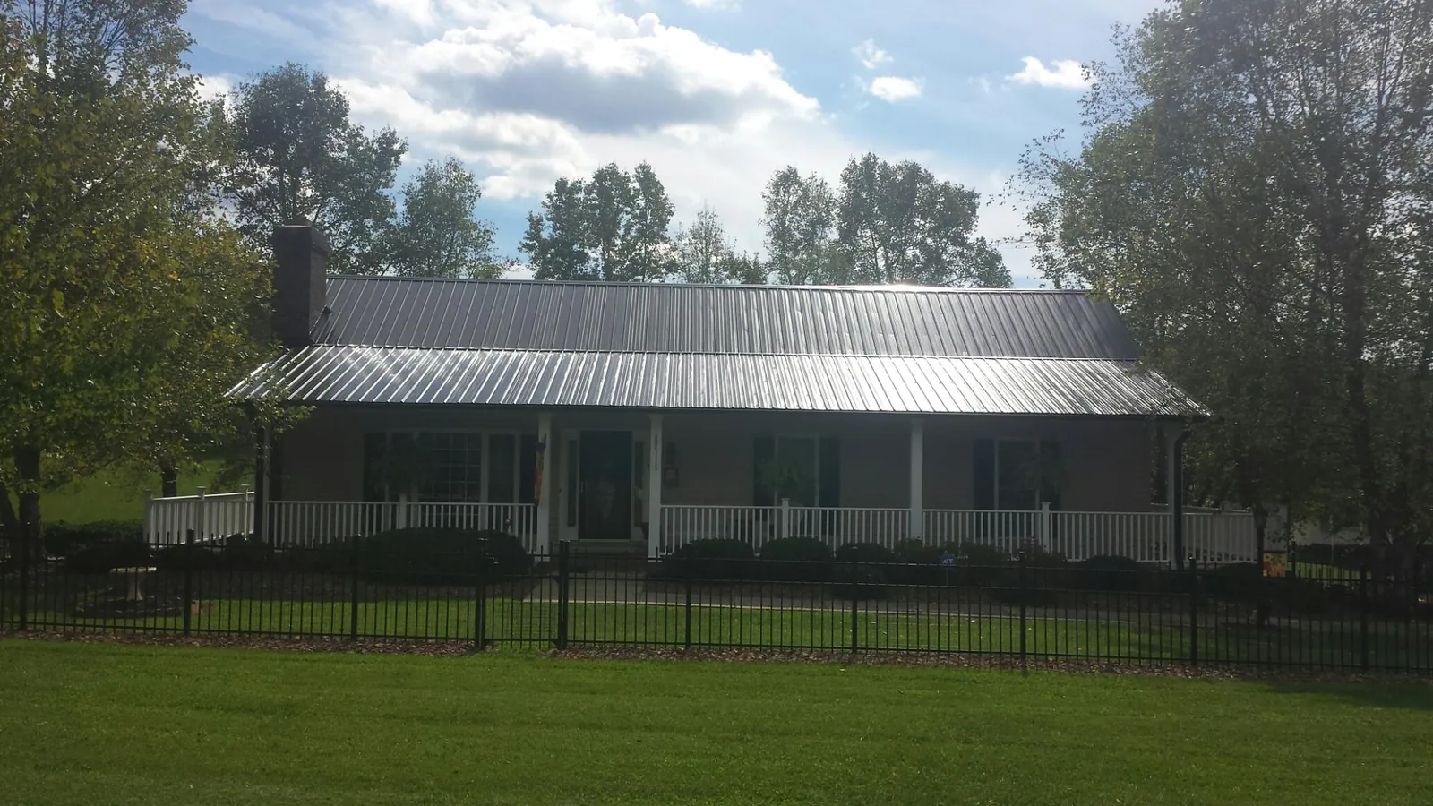 Gray metal roof on a brick ranch with a full width front porch — Gutter Guard Installation work by our crew in Skokie