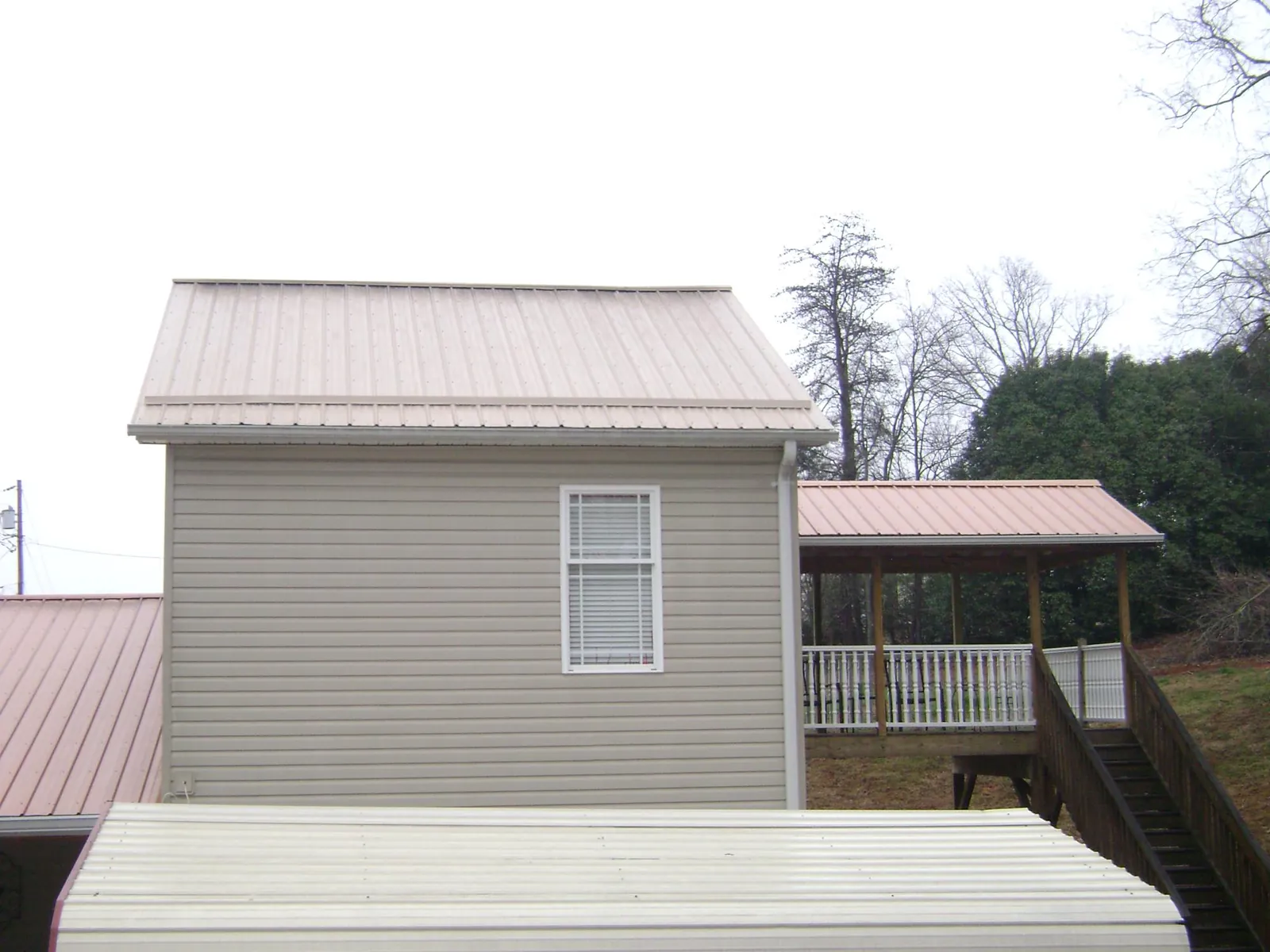 Tan metal roofs on a two story addition and attached porch, from a Roof Replacement job in Skokie