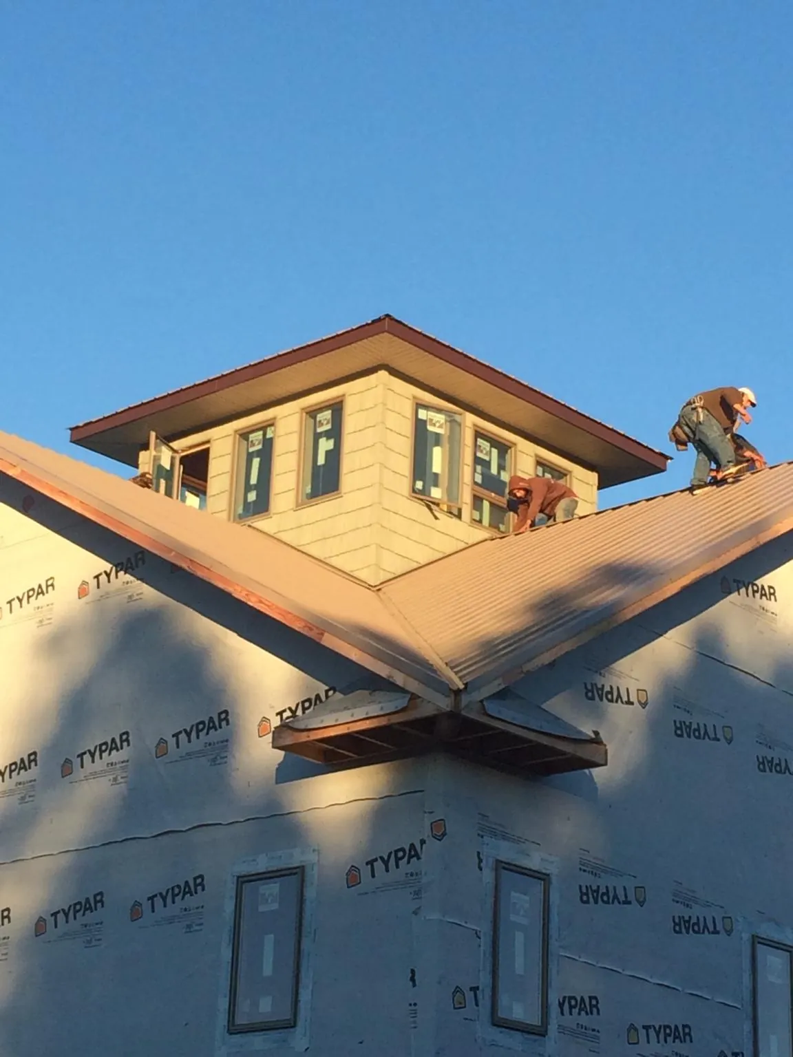 Roofers working around a rooftop cupola on a new metal roof at sunset — Roof Waterproofing in Skokie by Roofing Brothers